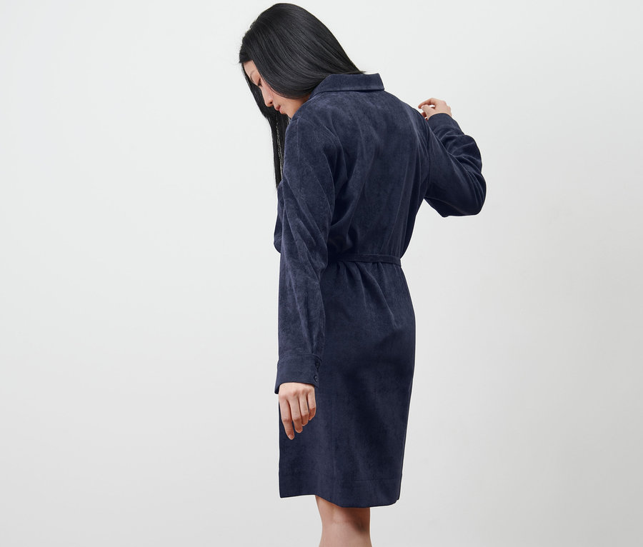 Žena se dívá dolů a má na sobě manšestrové šaty.