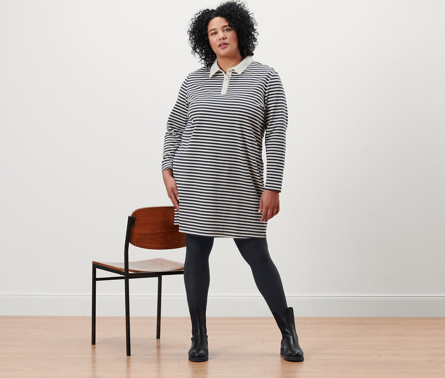 Žena pózuje v pruhovaných šatech z teplákoviny s polo límečkem a černých neprůhledných punčochových kalhotách (2 páry).