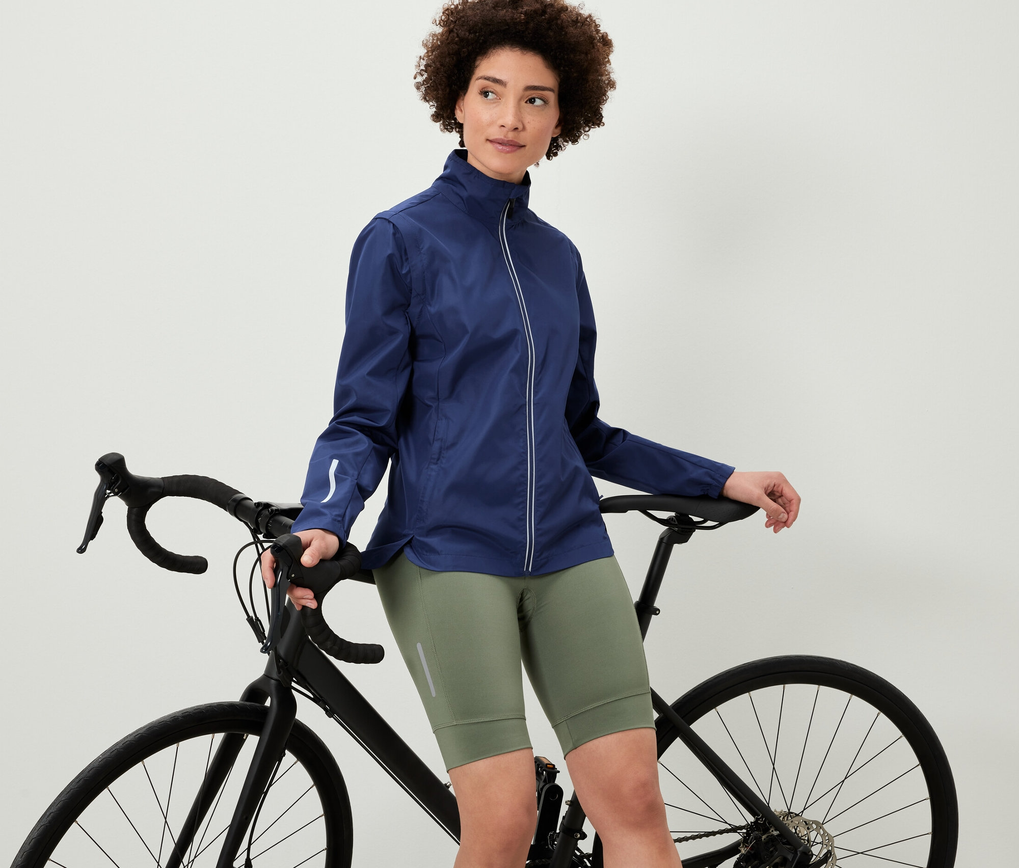 Žena opírající se o kolo má na sobě cyklistickou bundu 2 v 1.