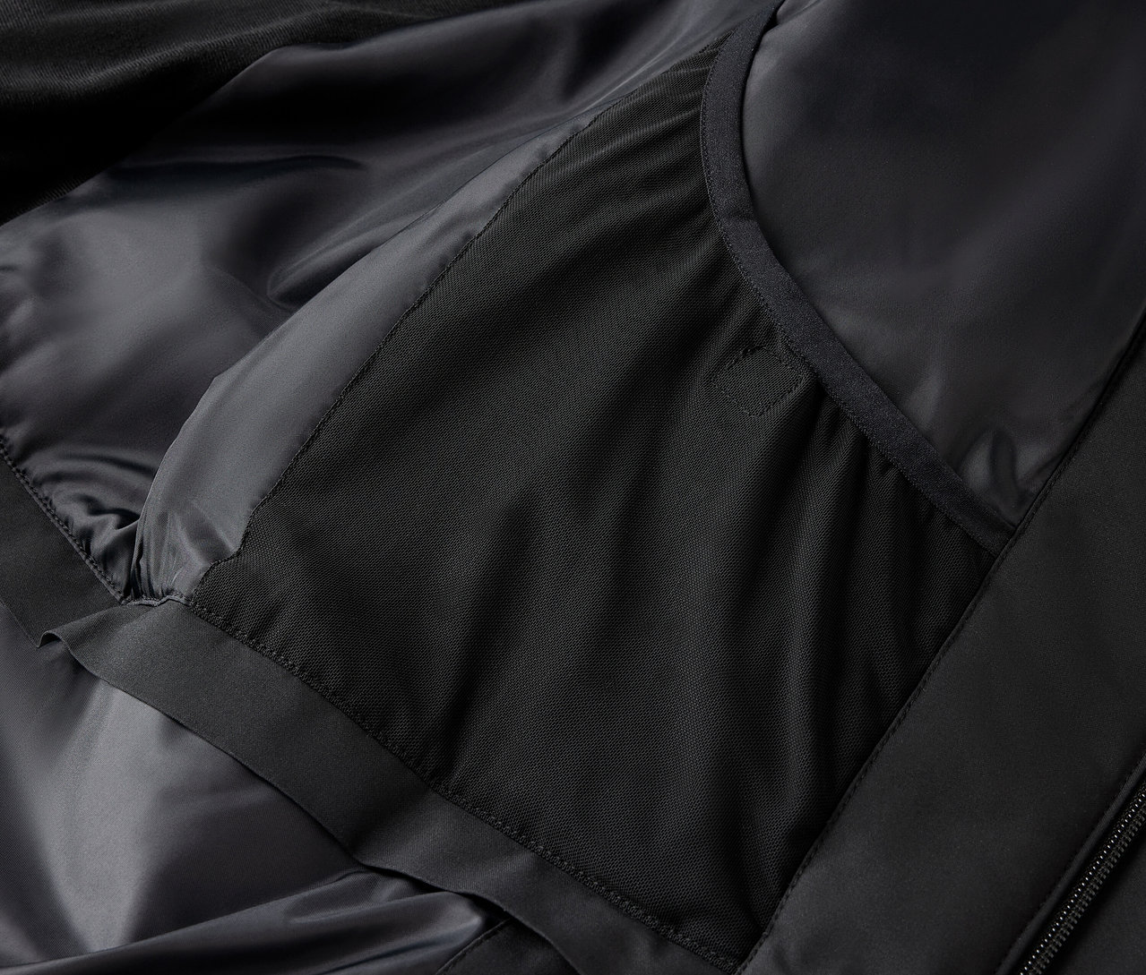 Detail černé bundy s vnitřní kapsou.