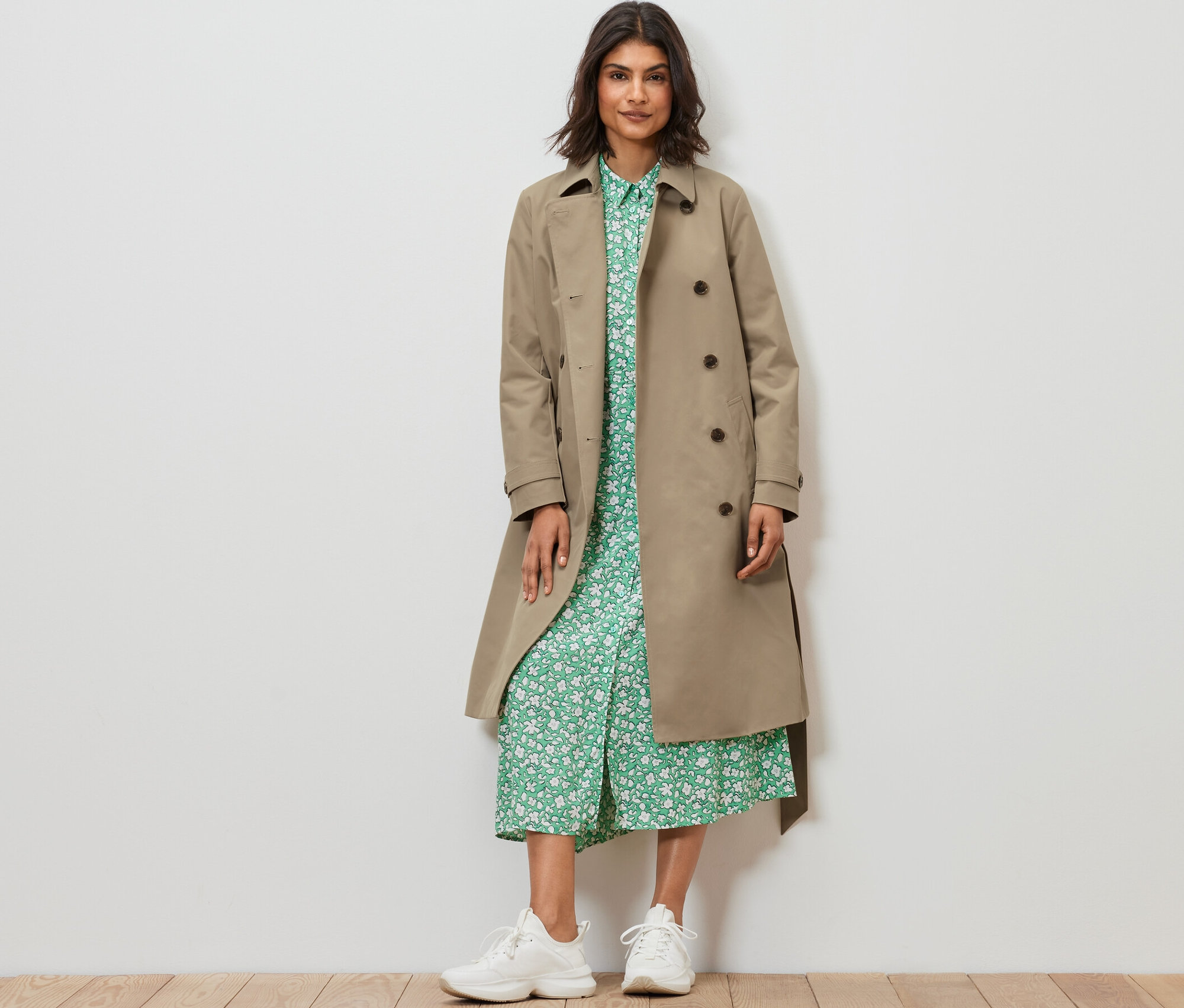 Žena stojící a má na sobě pískový trenčkot.