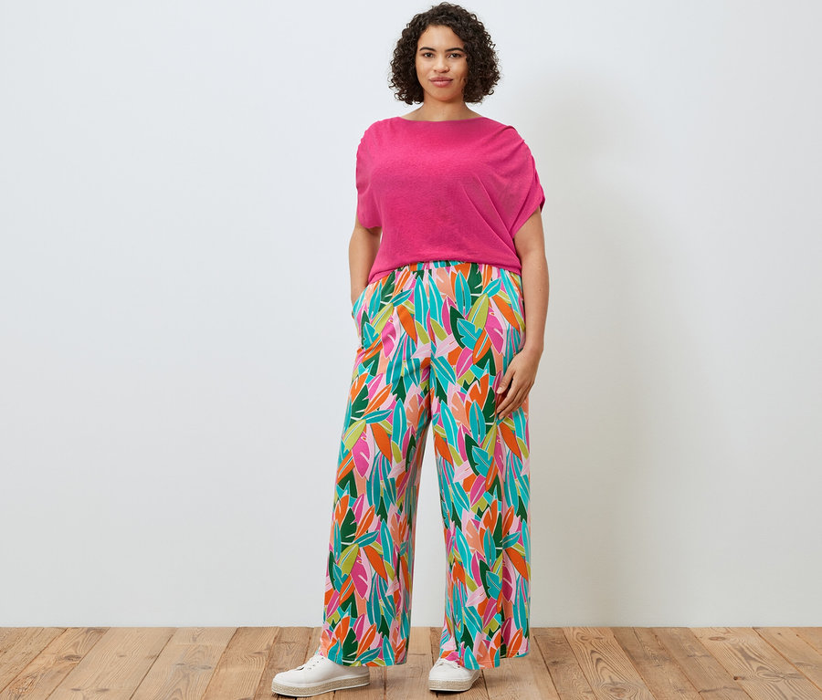 Žena pózuje v tričku ze směsi lnu a širokých kalhotách s potiskem.