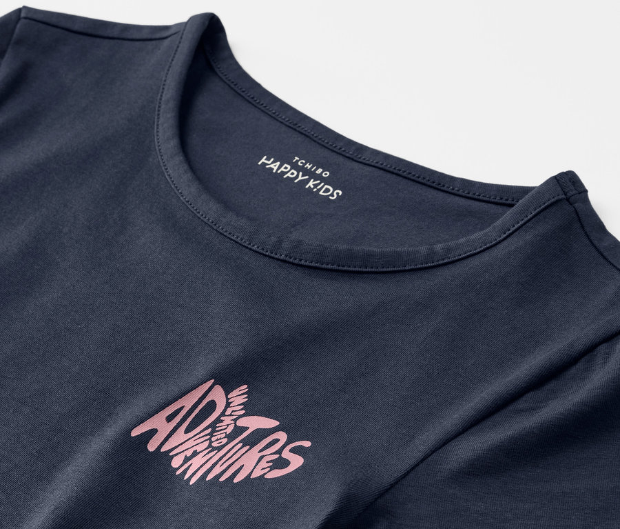 Detail modrého dětského trička s nápisem Adventures.