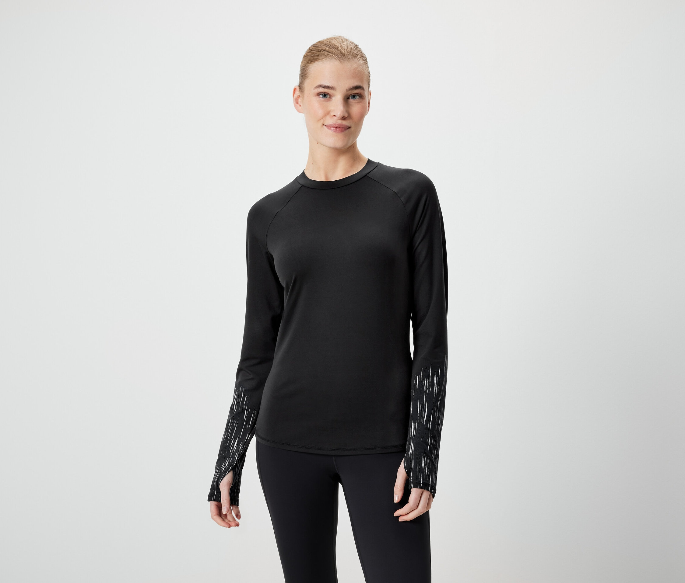 Žena má na sobě černé tričko s dlouhým rukávem a černé legíny.