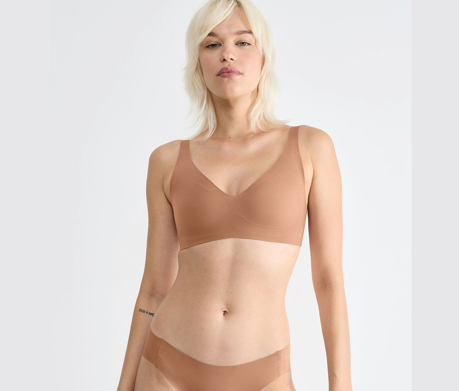 Blonďatá žena má na sobě hnědou podprsenku sloggi ZERO Feel 2.0 Soft Bra.