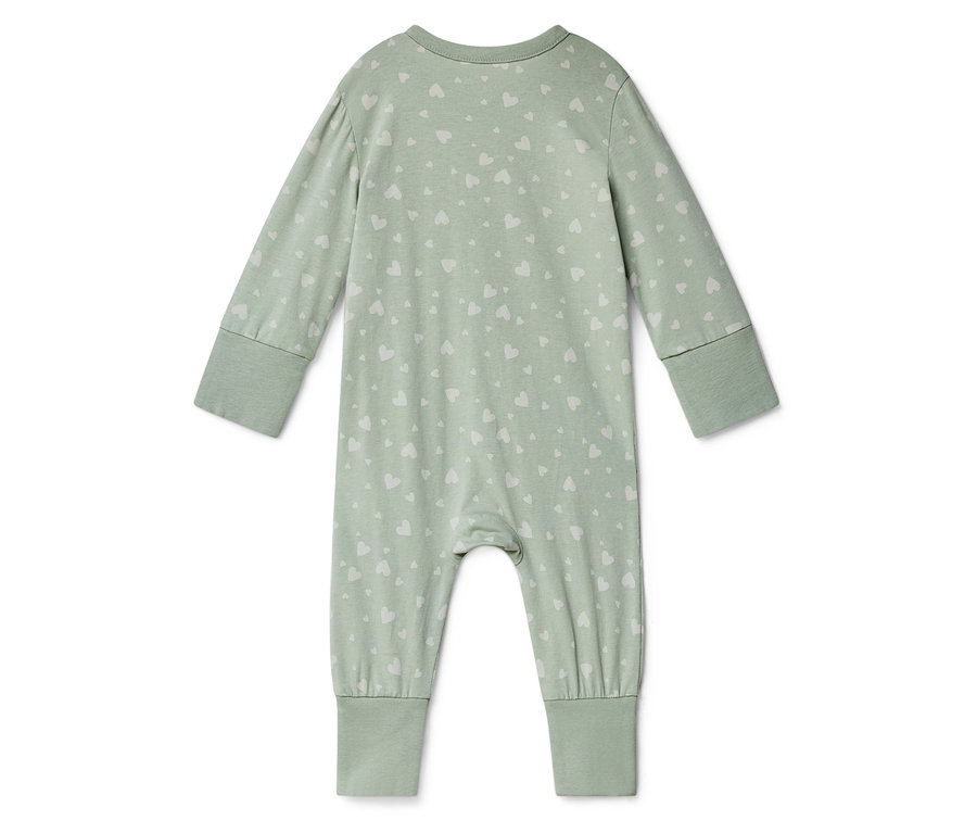 Světle zelený dětský overal s dlouhými rukávy a bílým vzorem srdce leží na bílém pozadí.