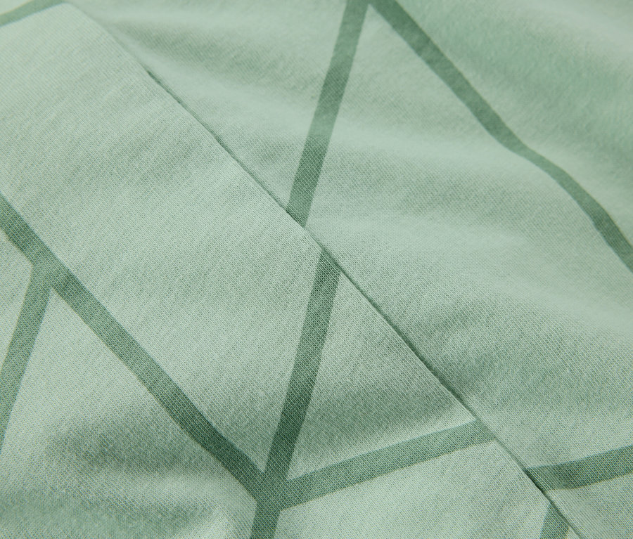 Detailní záběr světle zelené látky s geometrickým vzorem.