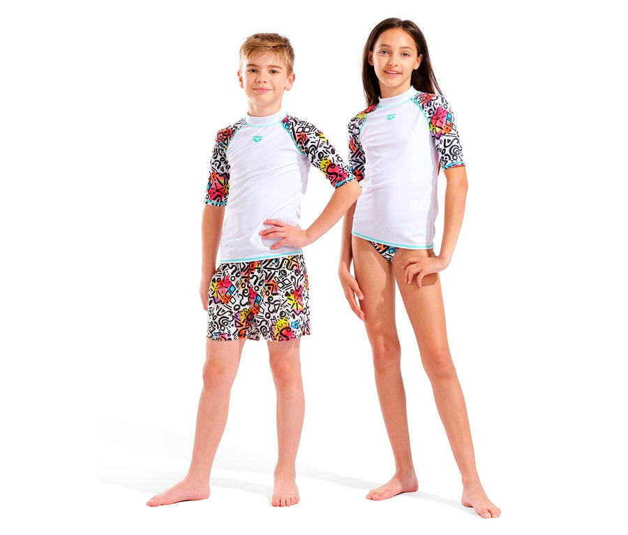 Dvě děti, chlapec a dívka, stojí vedle sebe na bílém pozadí. Oba mají na sobě bílé topy s barevnými rukávy a barevné spodky.