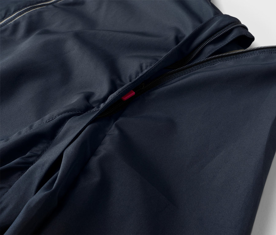 Detailní záběr na tmavě modrou bundu s částečně rozepnutým zipem.