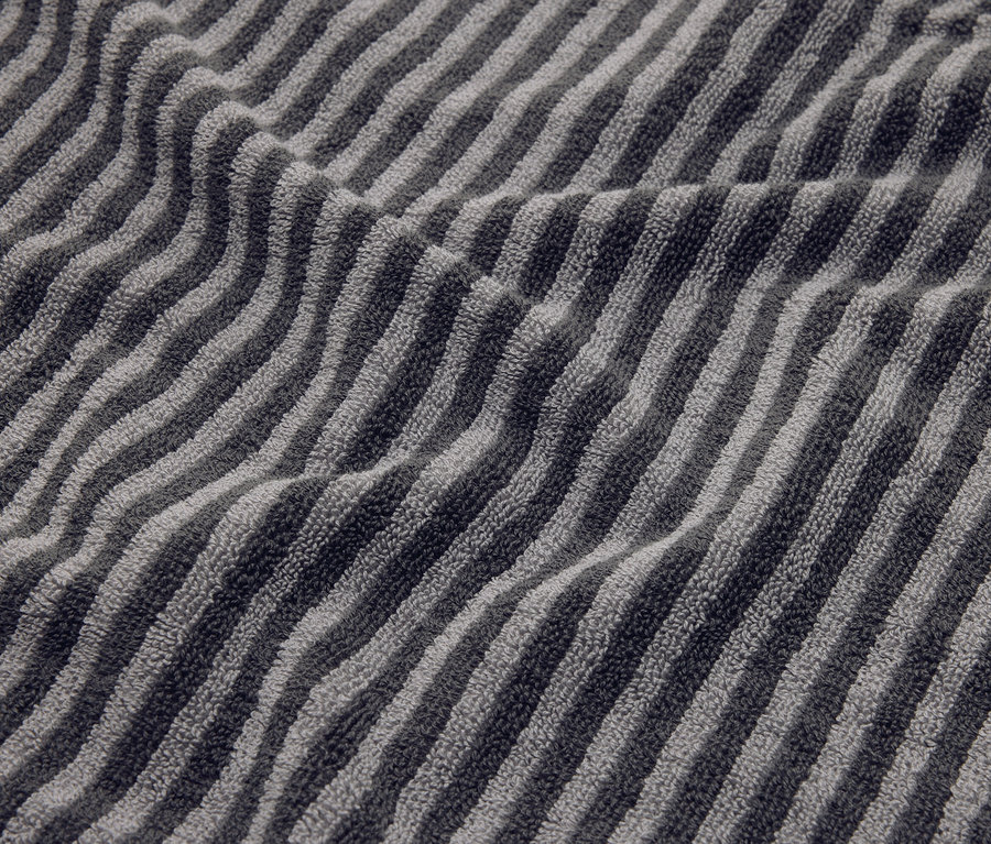 Detail pruhovaného šedého ručníku se záhyby.