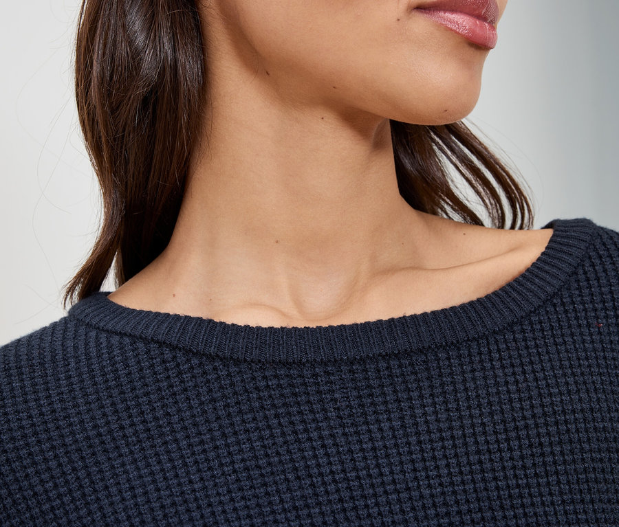 Detail ženy v tmavě modrém svetru.