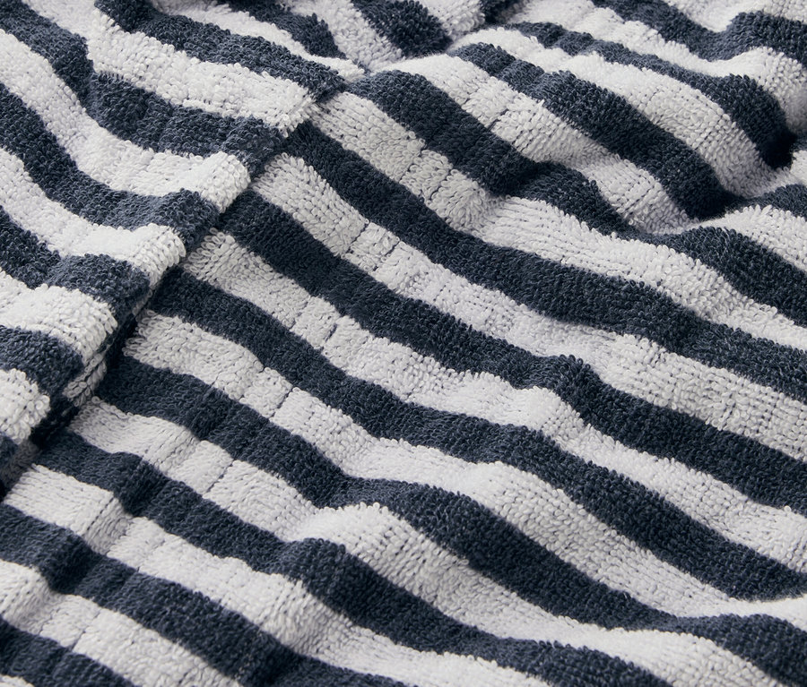 Detailní záběr na pruhovaný ručník s tmavě modrými a bílými pruhy.