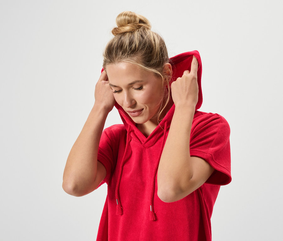 Žena s drdolem má na sobě červenou mikinu s kapucí.