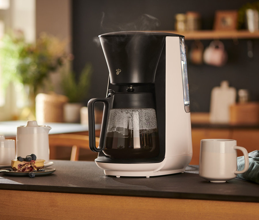 Bílý překapávač na kávu »Let's Brew« stojí na stole vedle šálku, konvičky na mléko, cukřenky a talíře s koláčem.
