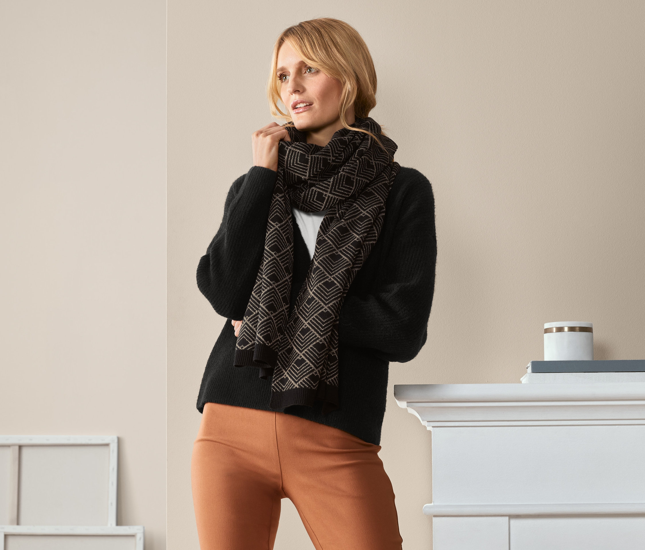 Žena pózuje v pletené šále se třpytivou přízí.