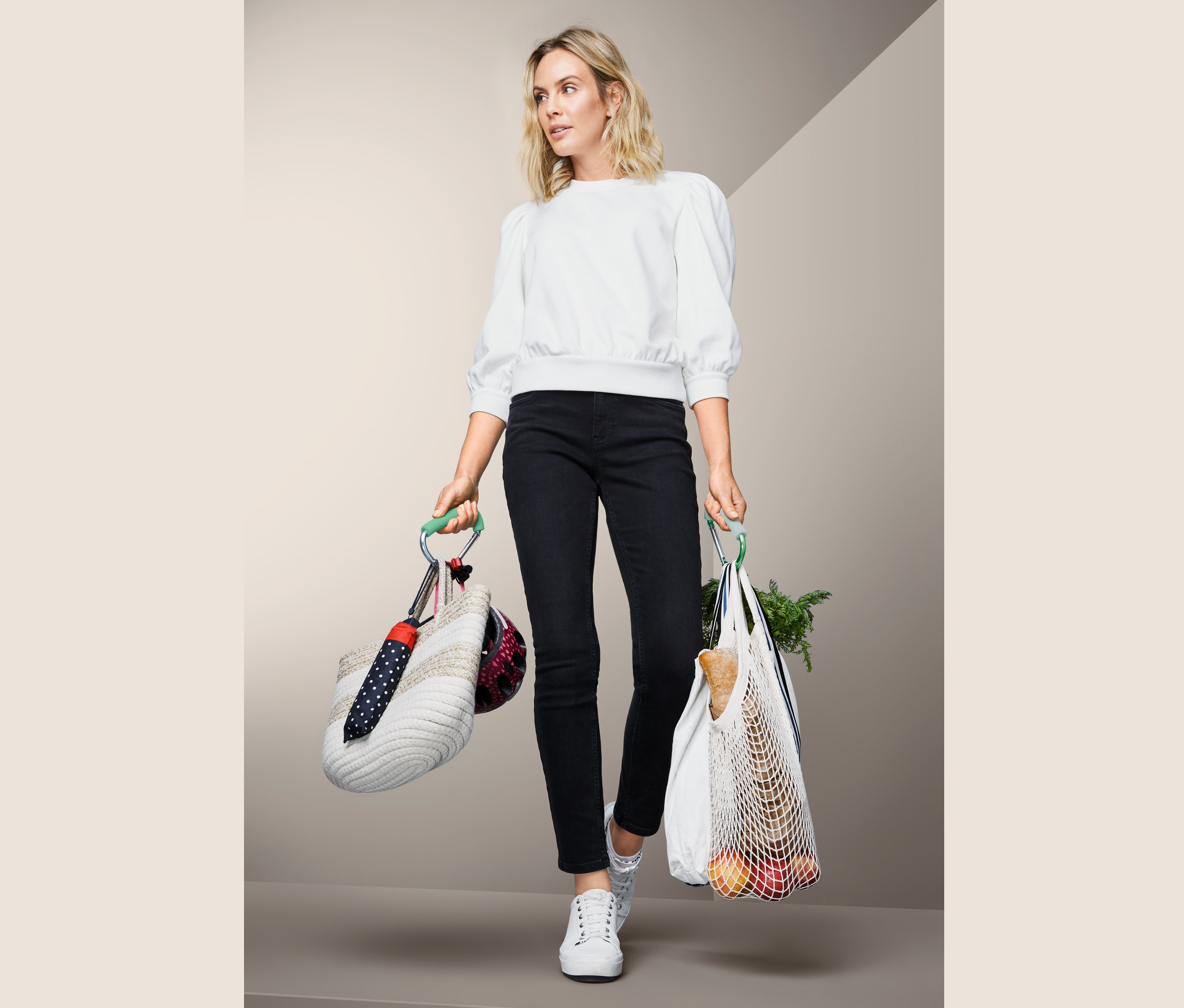 Žena drží tašku s helmou a deštníkem připevněnou pomocí 2 ks XXL karabin a nákupní tašku.