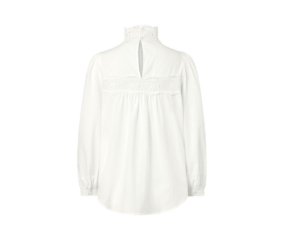 Detail bílé halenky s ažurovou výšivkou.