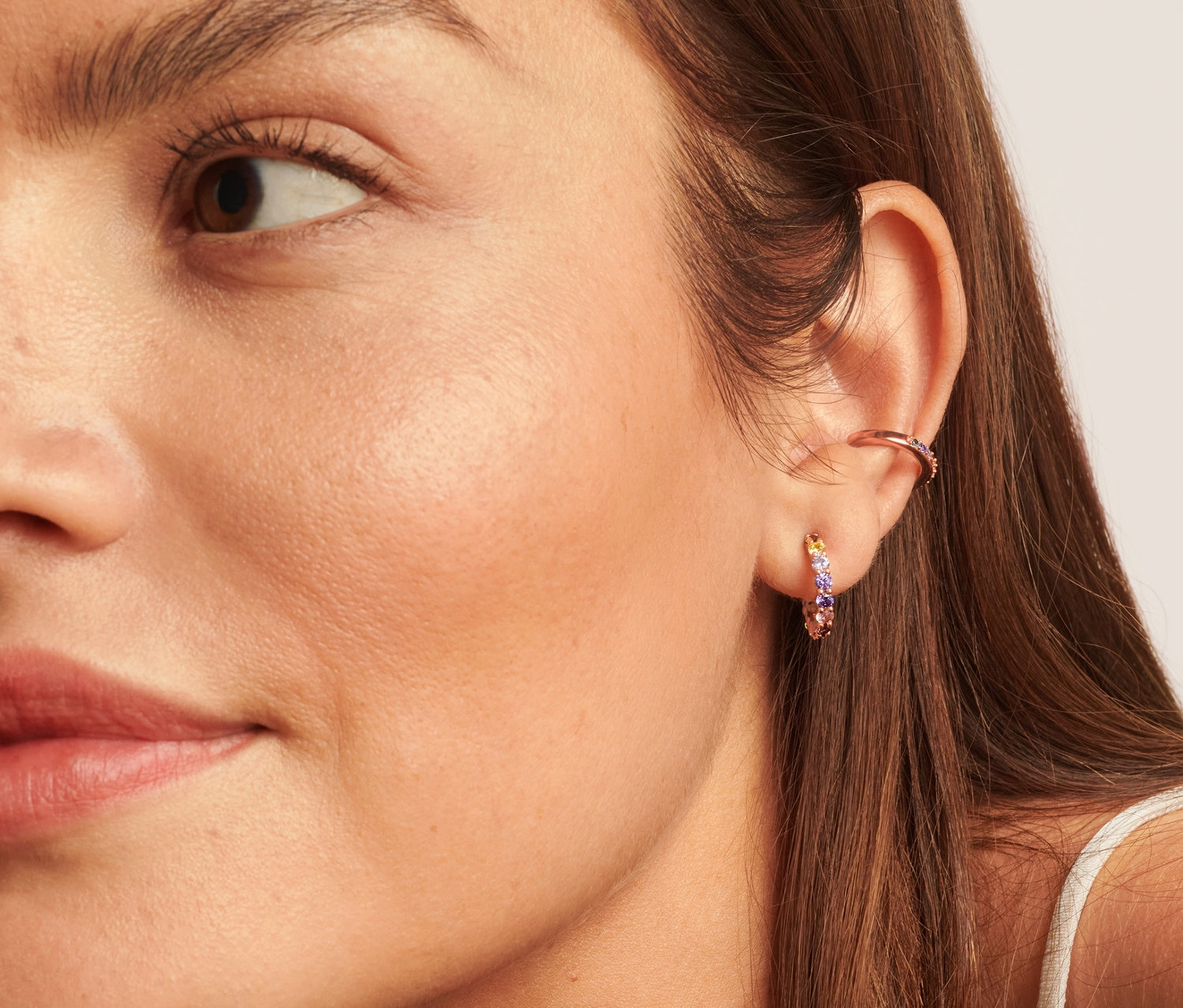 Detail obličeje ženy s vícebarevnými stříbrnými náušnicemi a náušnicemi Ear cuff.