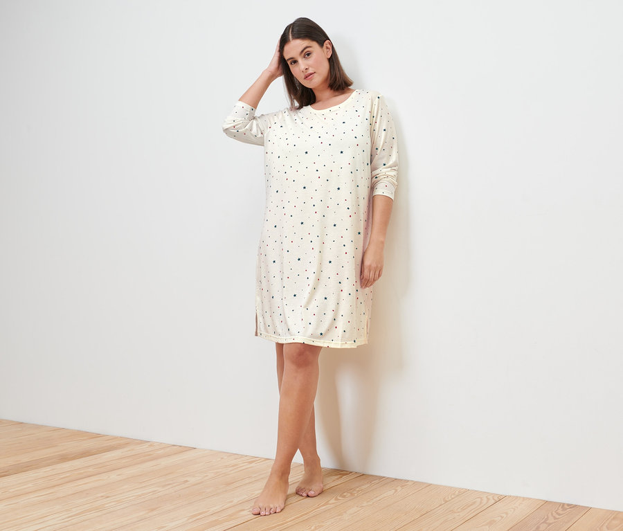 Žena pózuje v krémové noční košili.