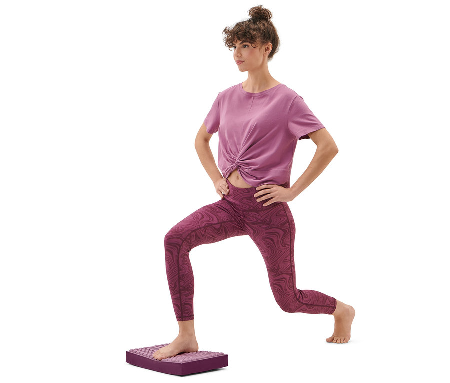 Žena cvičí výpad na balanční a masážní podložce.