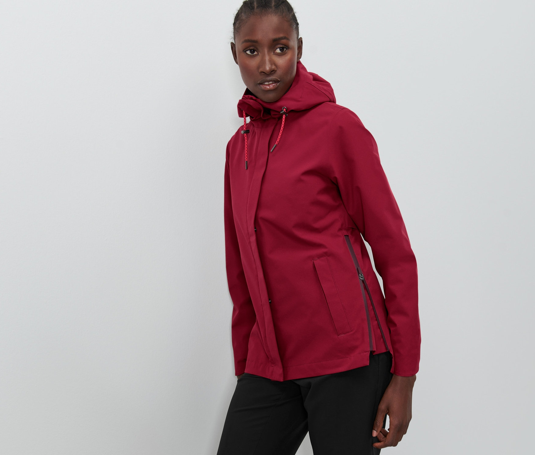 Žena pózuje v bordó outdoorové bundě.