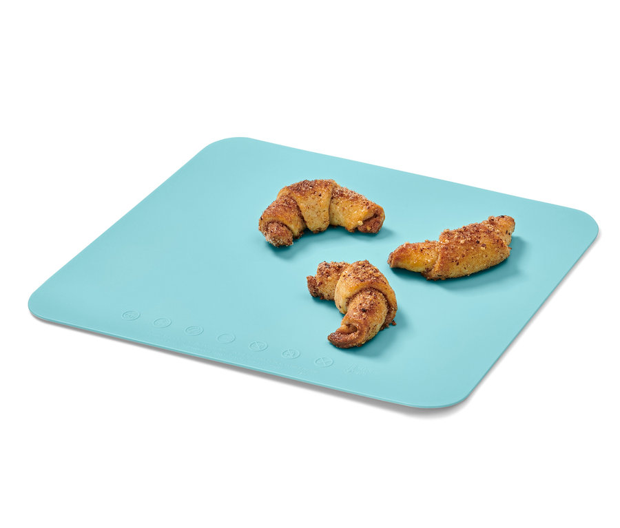 Tři croissanty leží na modré pečicí podložce na makronky.