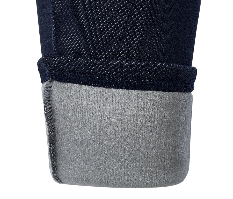 Detail tmavě modrých džegin s ohrnutým lemem, odhalujícím šedou podšívku.