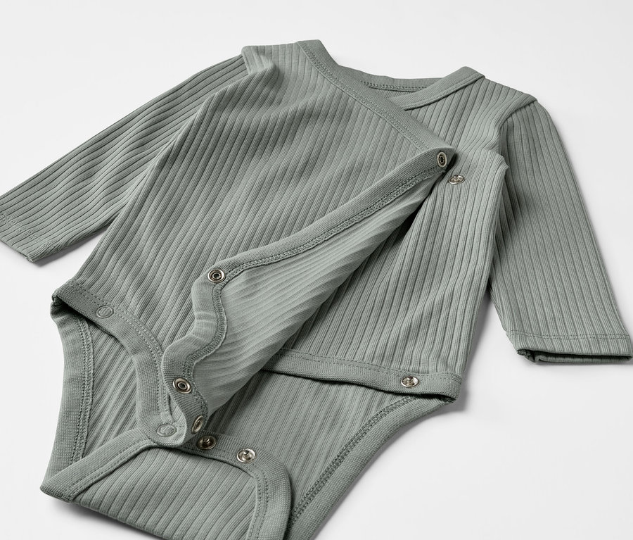 Dvě šedozelená žebrovaná body s dlouhým rukávem pro miminka leží na sobě.