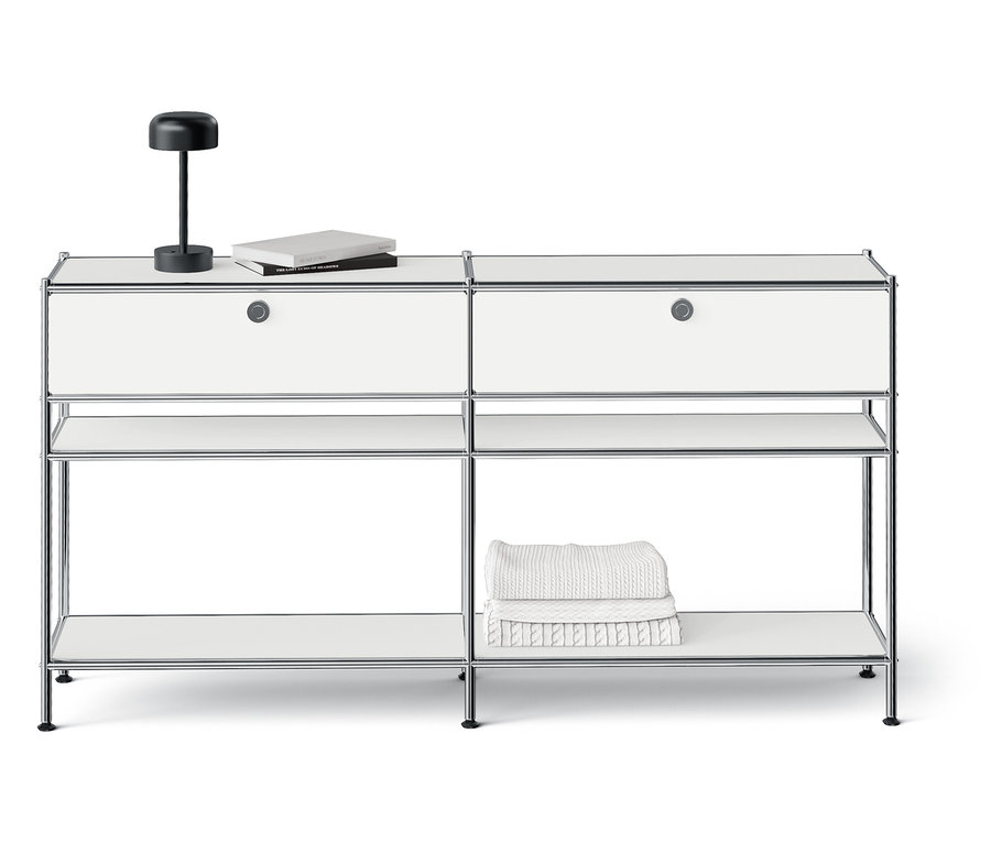 Bílý modulární úložný systém se dvěma zásuvkami, otevřenými policemi a lampou nahoře.