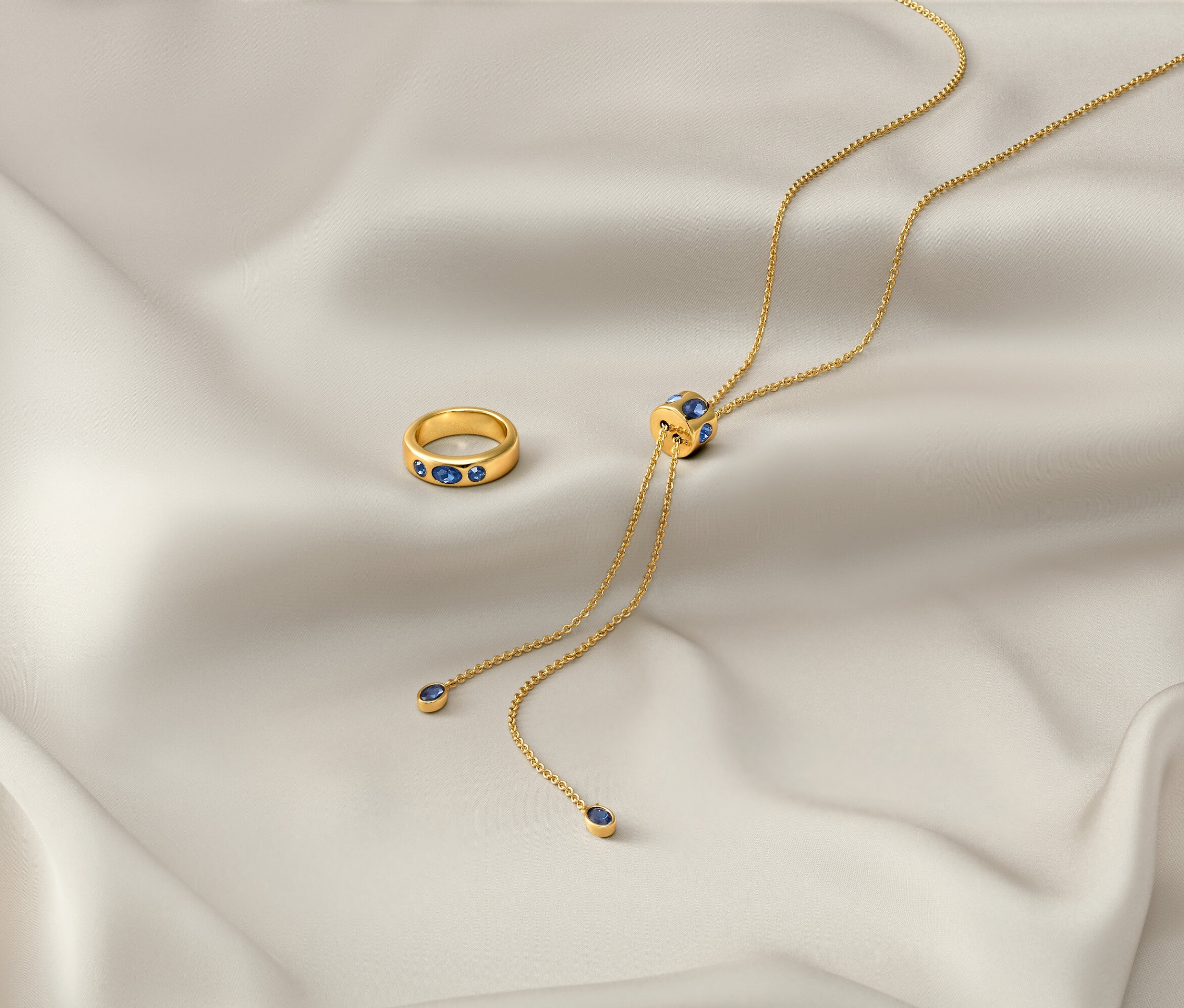 Na bílé látce leží zlatý řetízek »Iconic« a zlatý prsten »Iconic«.