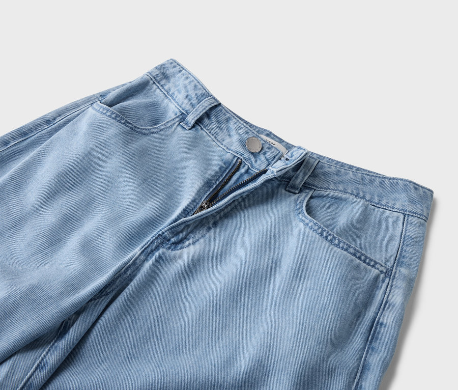 Detailní pohled na světle modré džíny s viditelným zipem a kapsami.