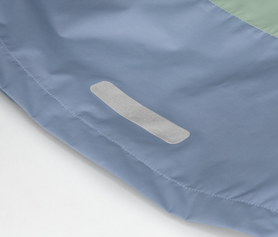 Detailní záběr modrozelené bundy s reflexním pruhem na straně.