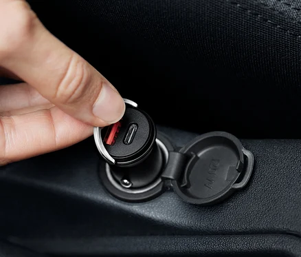 Ruka připojuje černou nabíječku do auta USB-C.