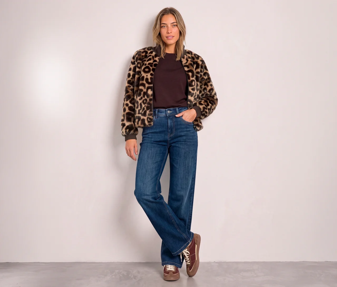 Žena má na sobě Bluzon Street One s leopardím vzorem, hnědý top, široké džíny a hnědé šněrovací boty.