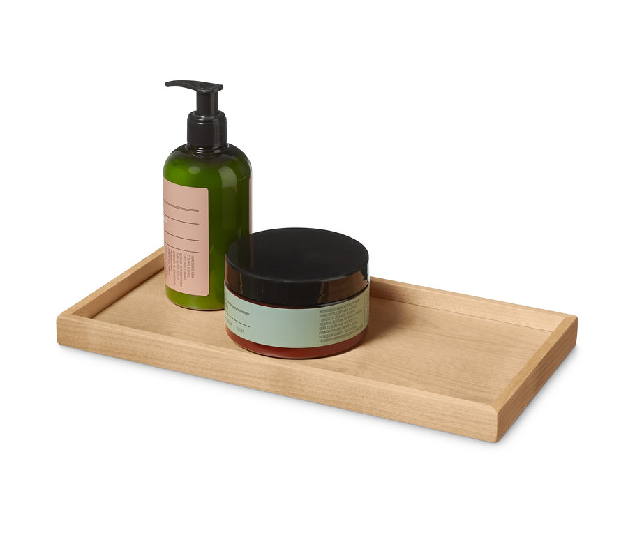 Zelená láhev a dóza s černým víčkem na dřevěném podnosu.