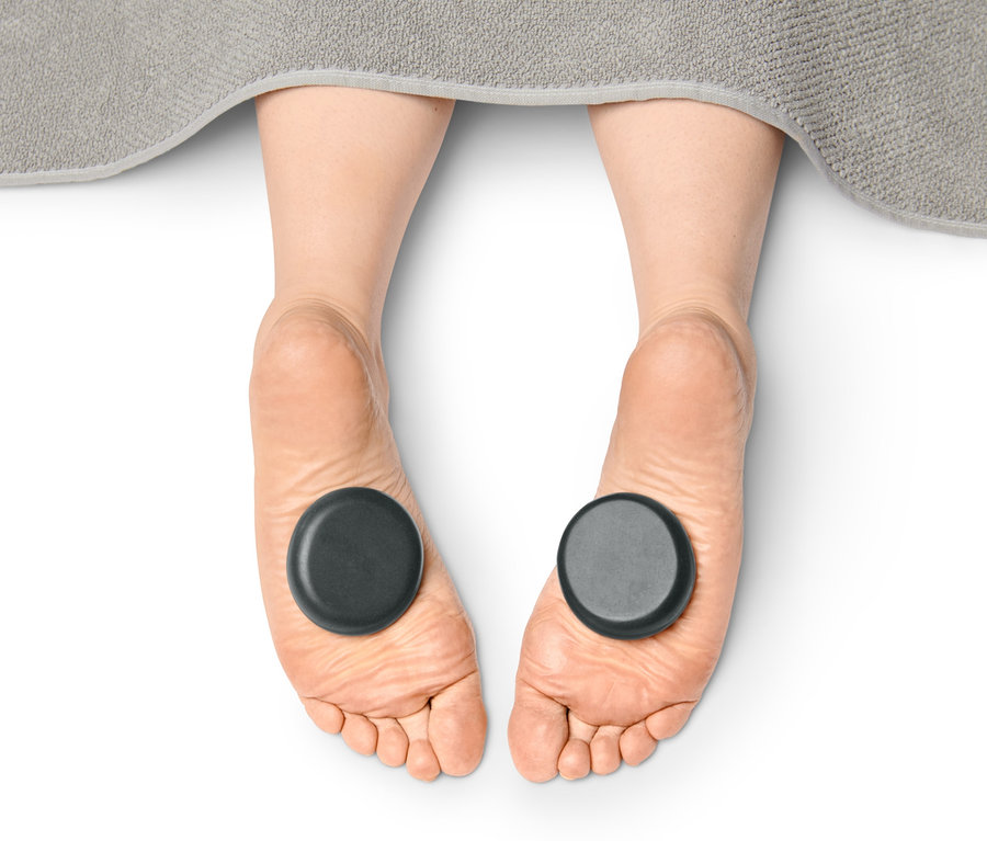 Nohy s masážními lávovými kameny.