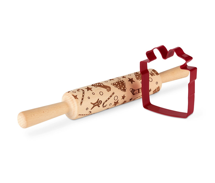 Váleček na těsto s motivy a červená vykrajovátka na sušenky ve tvaru dárku.