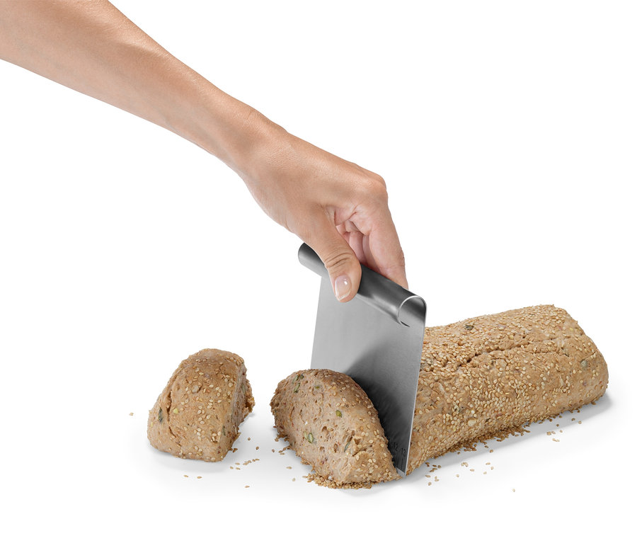 Ruka krájí chleba pomocí sady pomůcek na pečení.