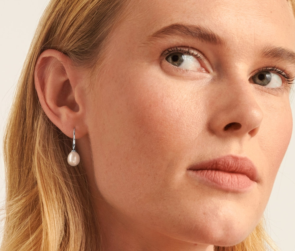 Blondýna má na sobě stříbrný řetízek 925 s barokními sladkovodními perlami z řízeného chovu a náušnice, stříbro 925, s uměle pěstovanými sladkovodními perlami.