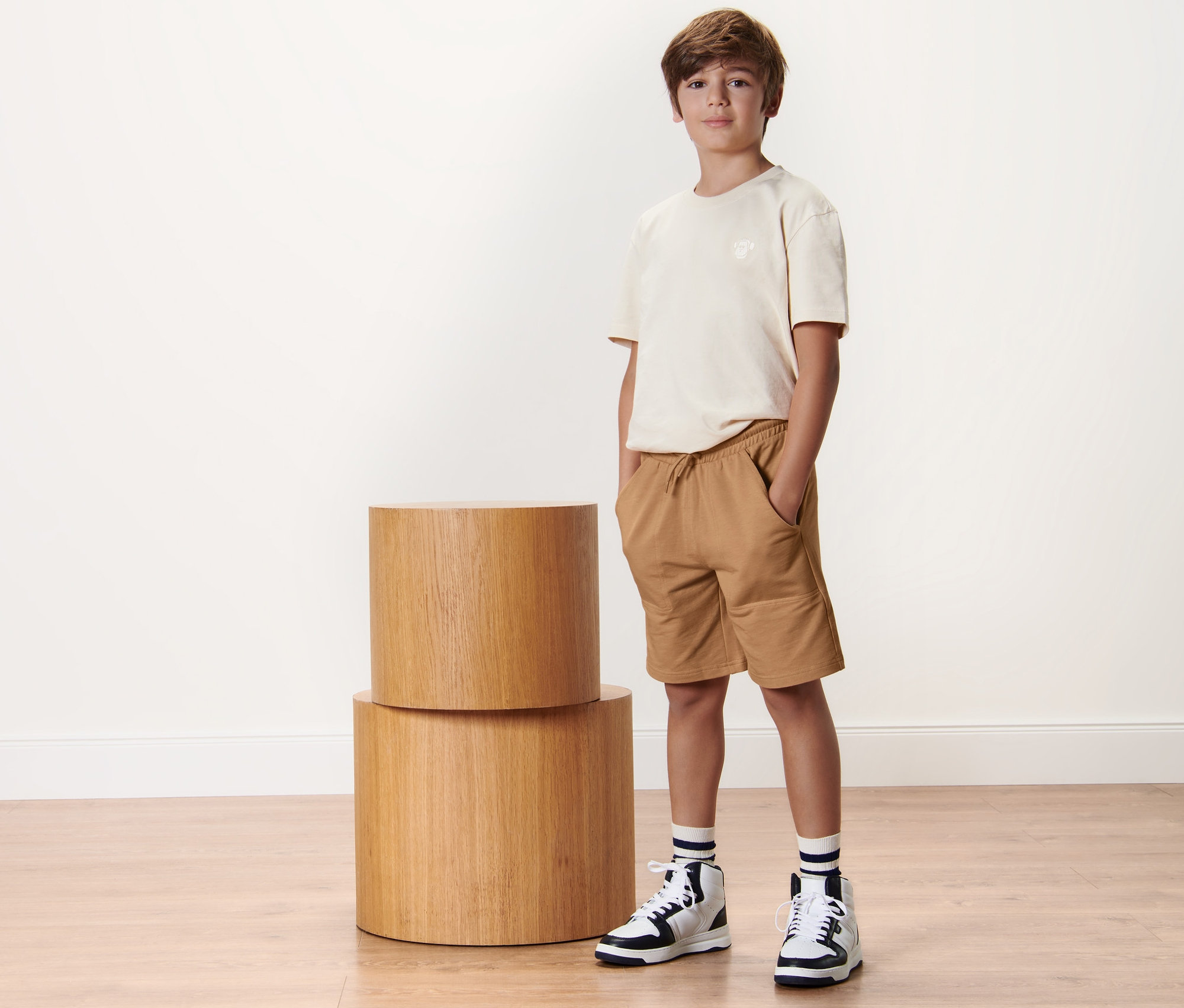 Chlapec stojí vedle sebe se dvěma dětskými teplákovými šortkami.