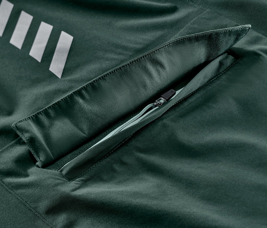 Detail cyklistické bundy do deště se stříbrnými pruhy a kapsou na zip.