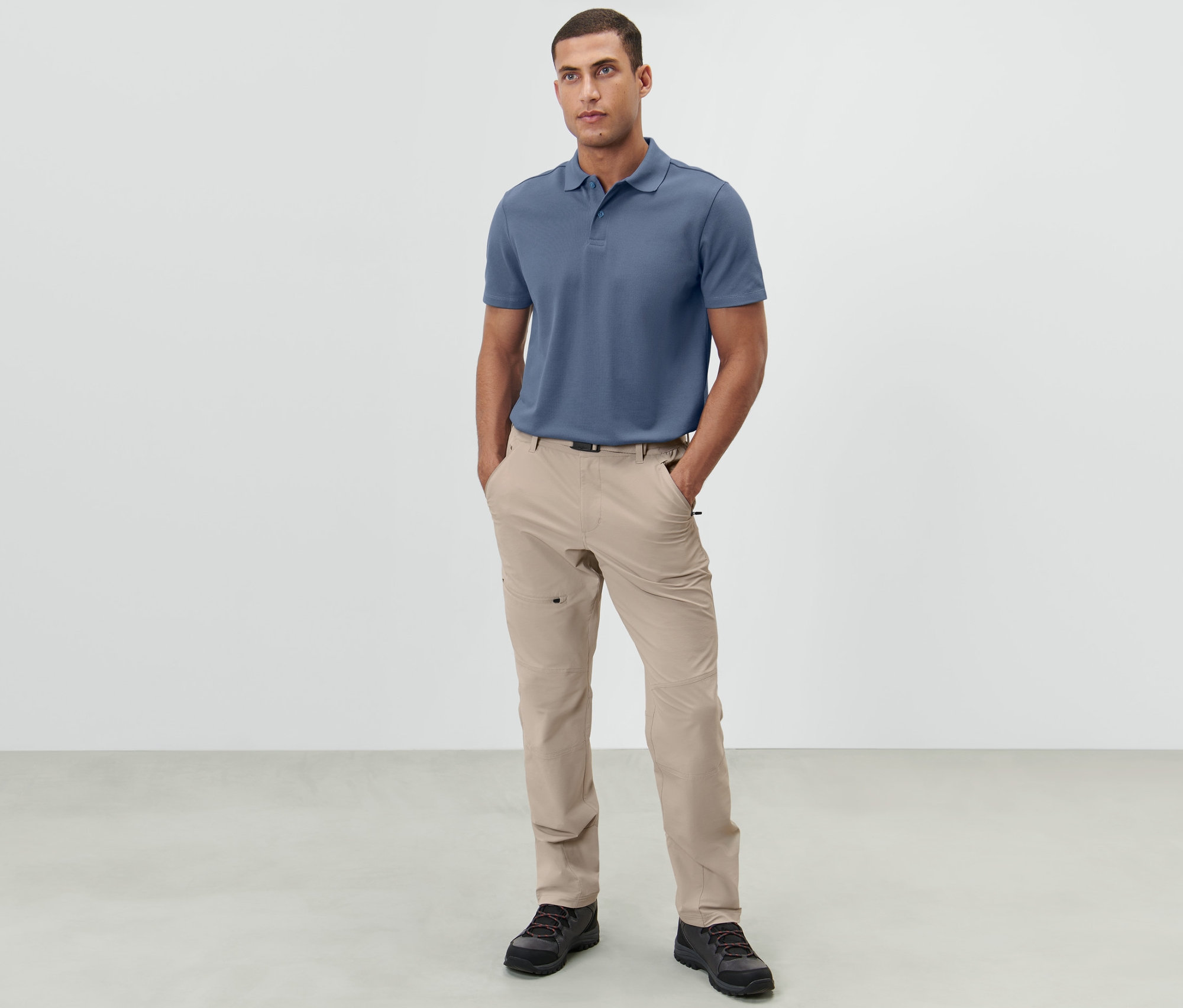 Muž stojí a má ruce v kapsách světle béžových outdoorových kalhot.