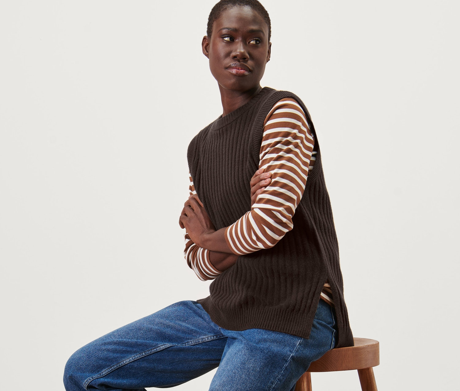 Žena sedí na stoličce a má na sobě pletenou vestu.