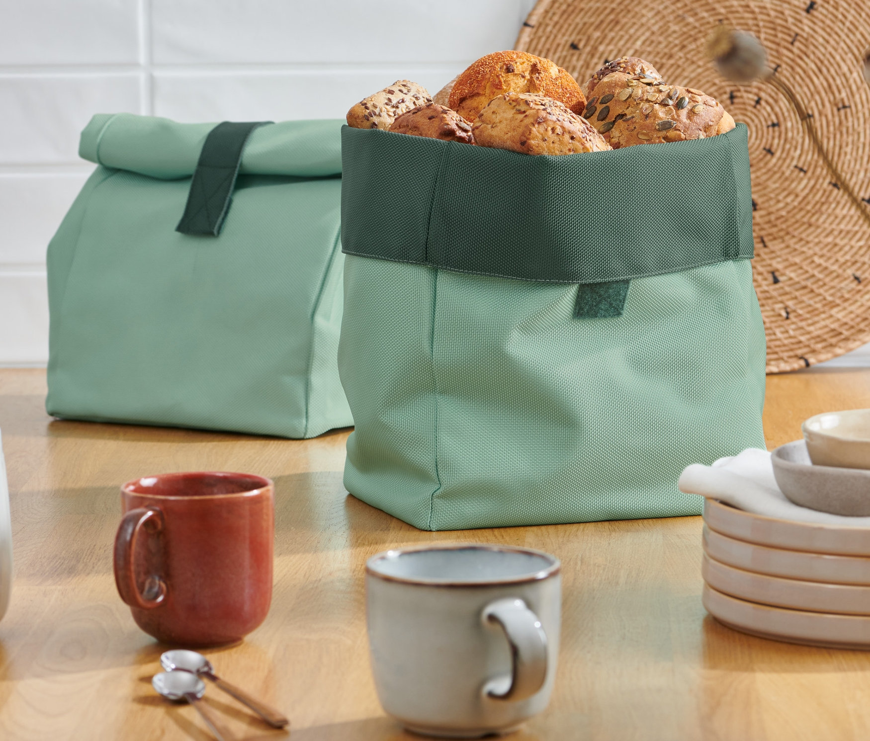 Dva zelené vaky na chléb 2 v 1 stojí na dřevěném stole.