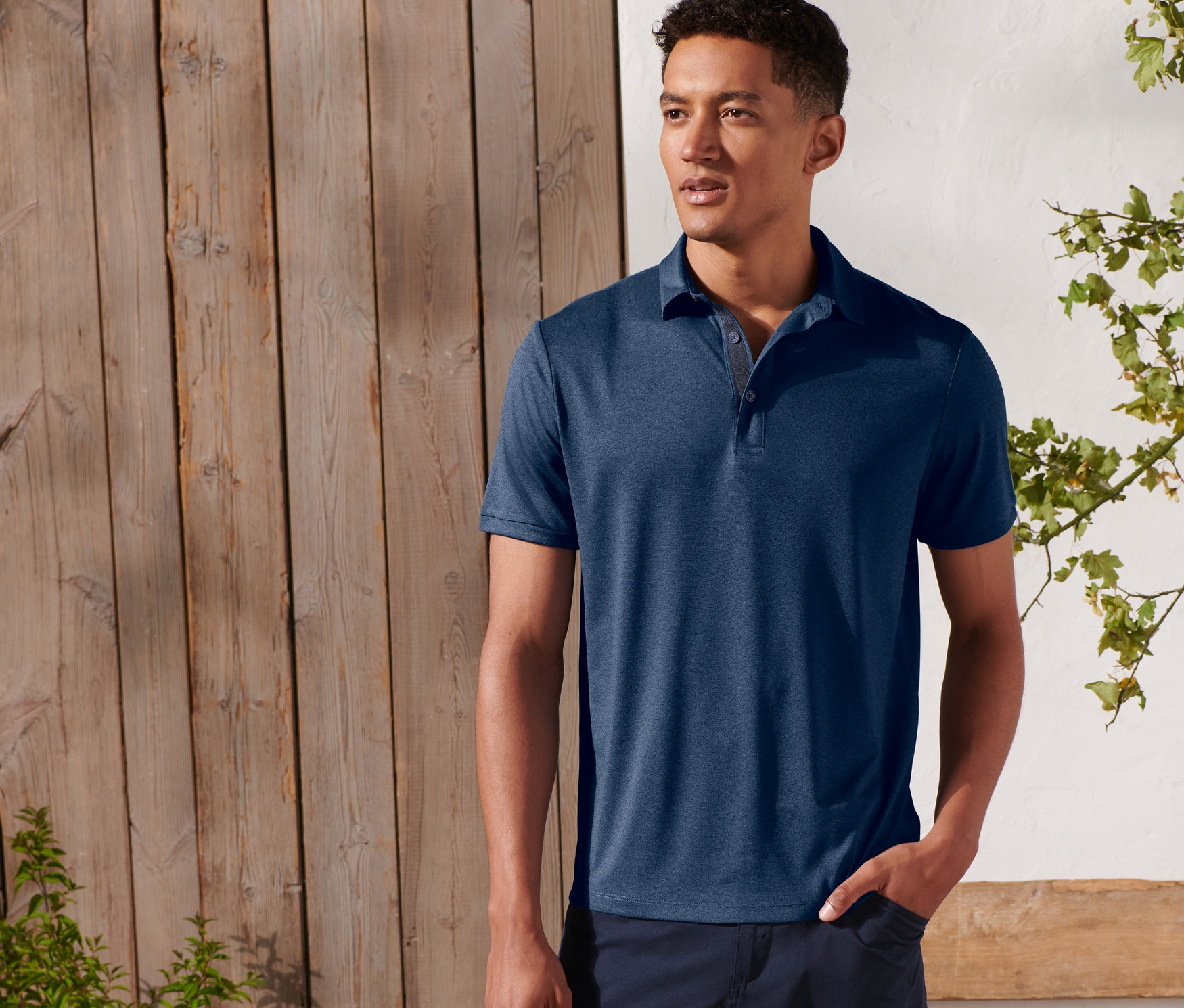 Muž pózuje venku a má na sobě funkční polokošili.