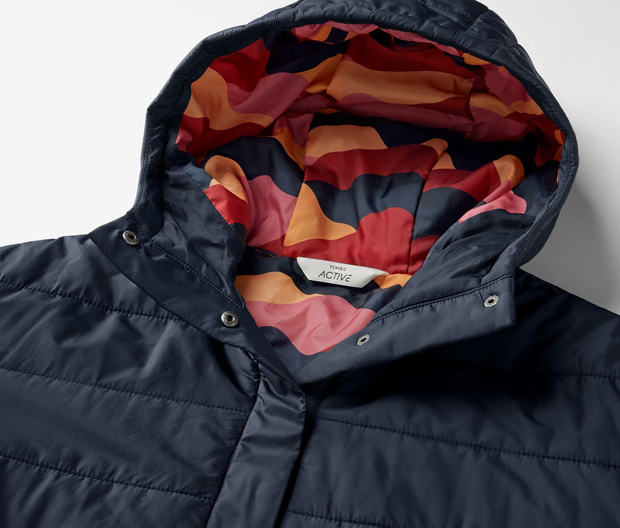Detail modrého outdoorového ponča s kapucí s barevným vzorem uvnitř.