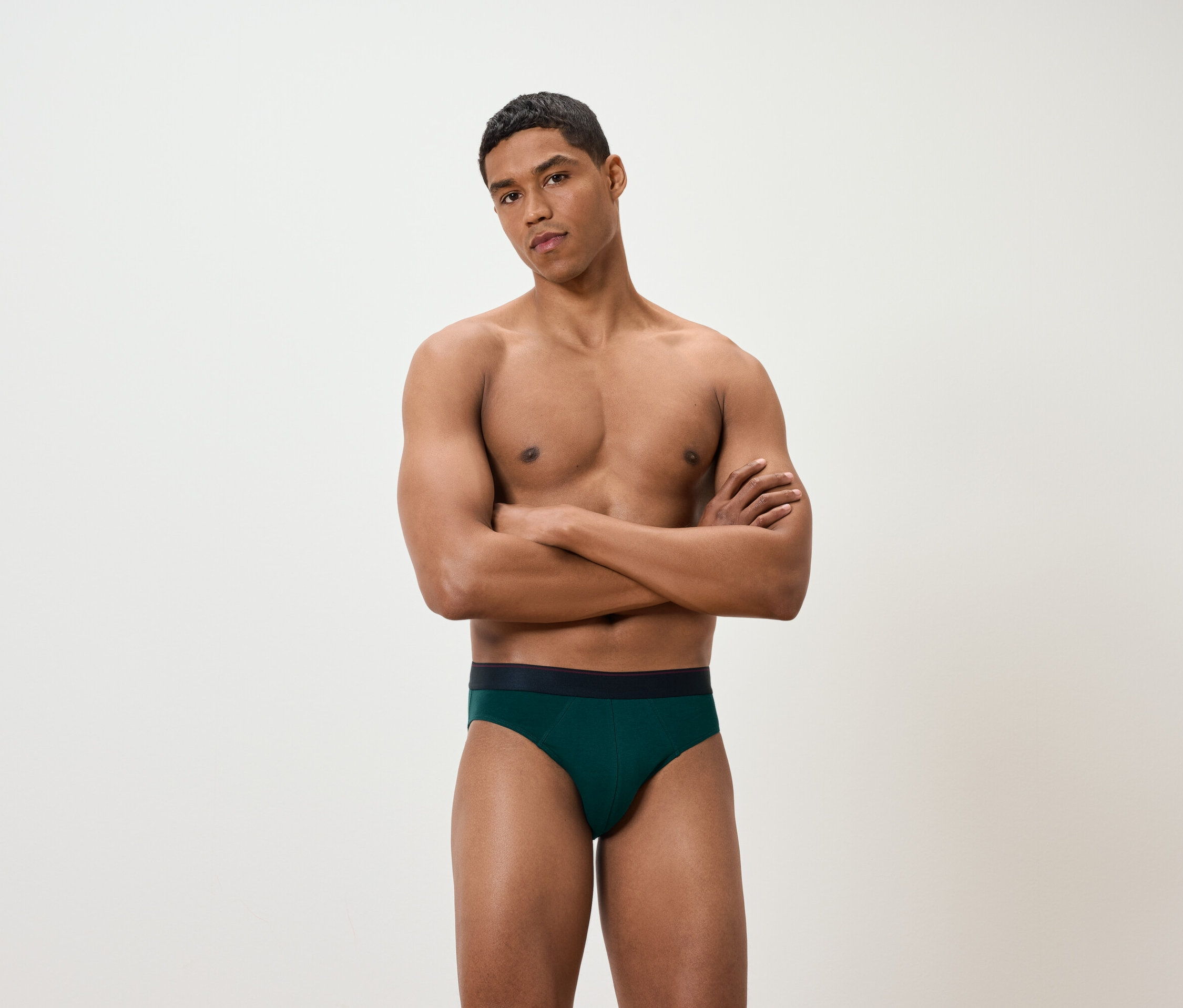 Muž se zkříženýma rukama má na sobě zelené slipy.