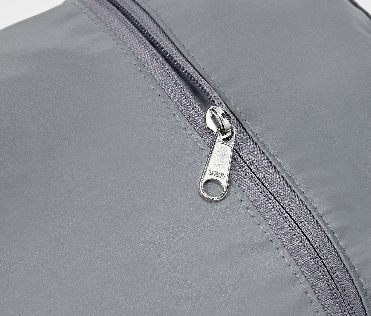 Detail šedého reflexního batohu se stříbrným zipem.