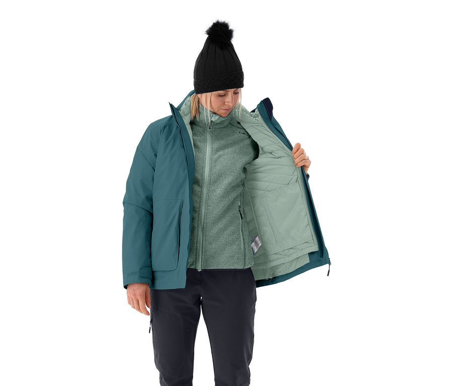 Žena otevírá multifunkční bundu CMP dámskou, má na sobě černou čepici s bambulí, fleecovou mikinu a černé kalhoty.