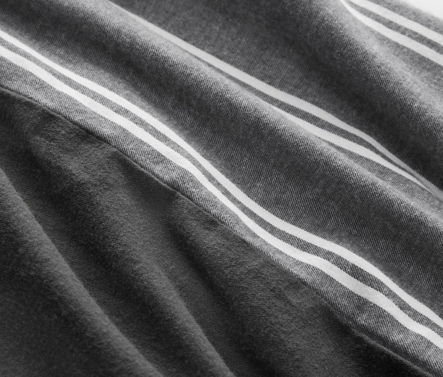 Detail šedé látky se třemi bílými pruhy.